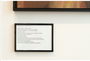 Nathan DeYoungs framed poem Silenced Layers - Perfectly Still, printed in black on white paper, is elegantly displayed in a thin black frame beside a vibrant acrylic painting, all set against a white wall.