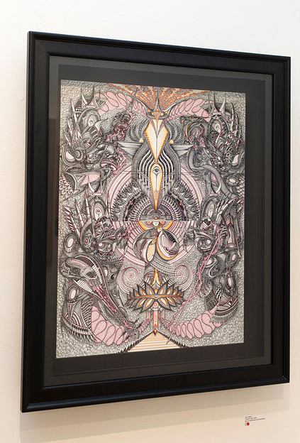Framed abstract artwork by Erik Siador, showcasing intricate patterns and swirling shapes in black and gray with touches of pink and yellow. Crafted with ink on Strathmore 500 illustration board, it displays symmetrical, organic forms akin to faces or figures.