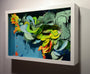 Crystal Wagners Terrarium VI is a 3D artwork featuring vibrant, swirling cut paper sculptures in a white frame. It combines green, blue, yellow, and orange hues on a deep blue background to create an abstract and dynamic scene.