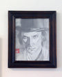 A graphite sketch by Calvin Wong features a person in a bowler hat with an intense expression. It has a red stamp in the lower left corner, suggesting Asian influence. The black and white artwork is framed in slightly worn wood and available for sale.