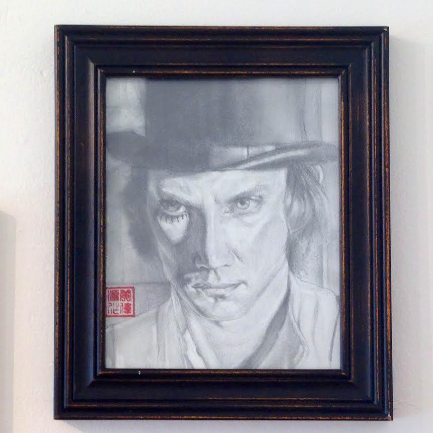 A graphite sketch by Calvin Wong features a person in a bowler hat with an intense expression. It has a red stamp in the lower left corner, suggesting Asian influence. The black and white artwork is framed in slightly worn wood and available for sale.