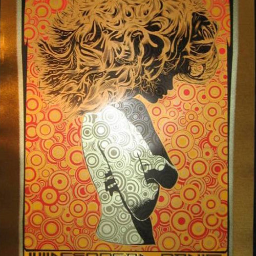 A Chuck Sperry psychedelic concert poster features a stylized silhouette with flowing hair against a vibrant, intricate background. Brushed gold foil accents highlight the text at the bottom announcing Widespread Panic and concert details, echoing Sperrys iconic style.