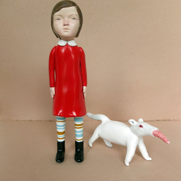Doubleparlours hand-sculpted resin artwork showcases a person with a calm expression in a red dress and striped socks, accompanied by a small white creature with an orange snout. Set against a neutral background and accented with acrylic paint, this masterpiece captures the viewers imagination.